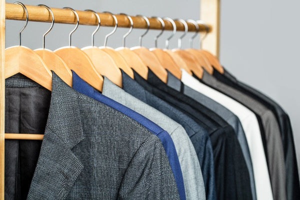 Vestes et costumes masculins suspendus sur un portant en bois